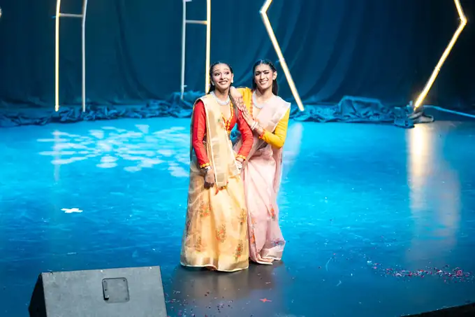 Dancers in gold sarees under a blue stage wash, Durban season