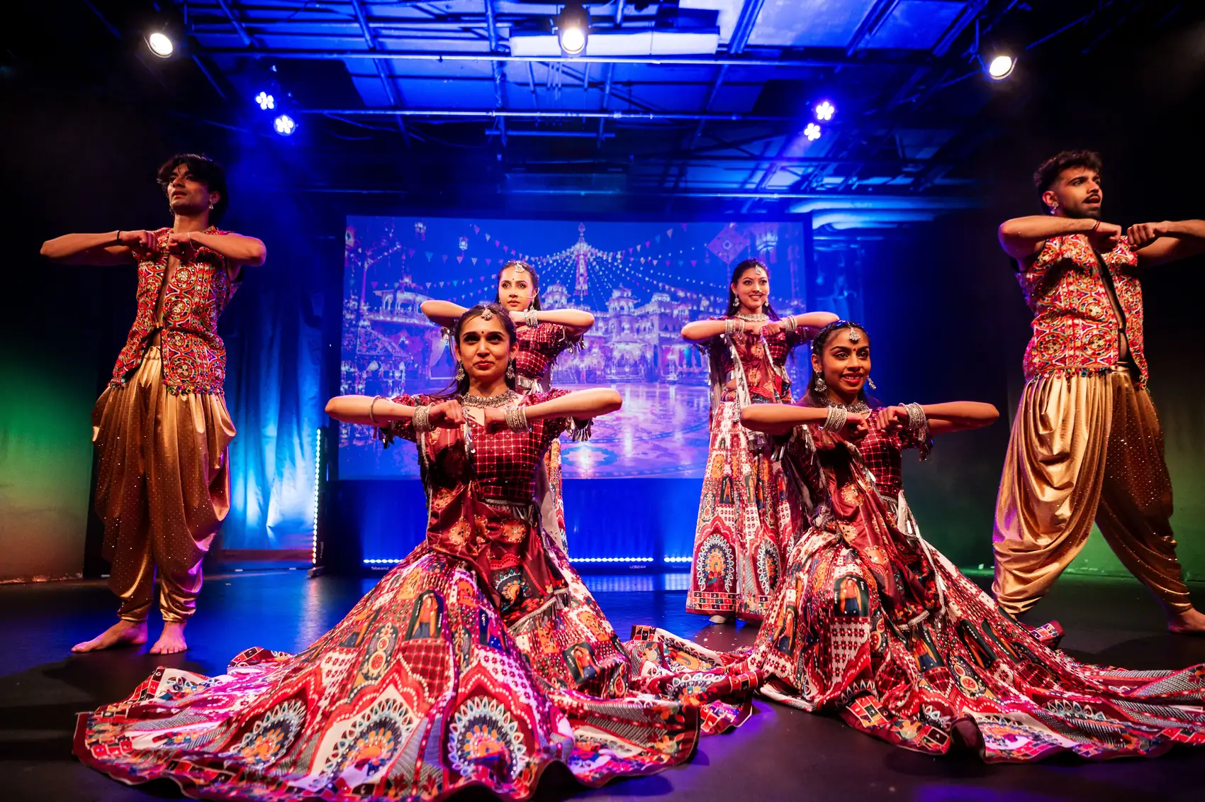Celestial Groove dancers in patterned lehengas seated in formation on stage during Dil Se Bollywood
