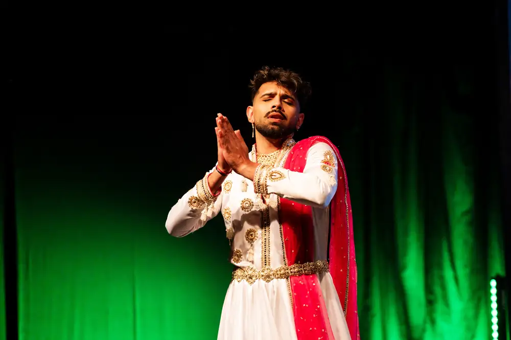 Soloist in white and gold costume performing under green stage light